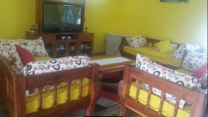 A living room with two wooden sofas, a television, and a cabinet. - Coral Sea Villas (Malindi)