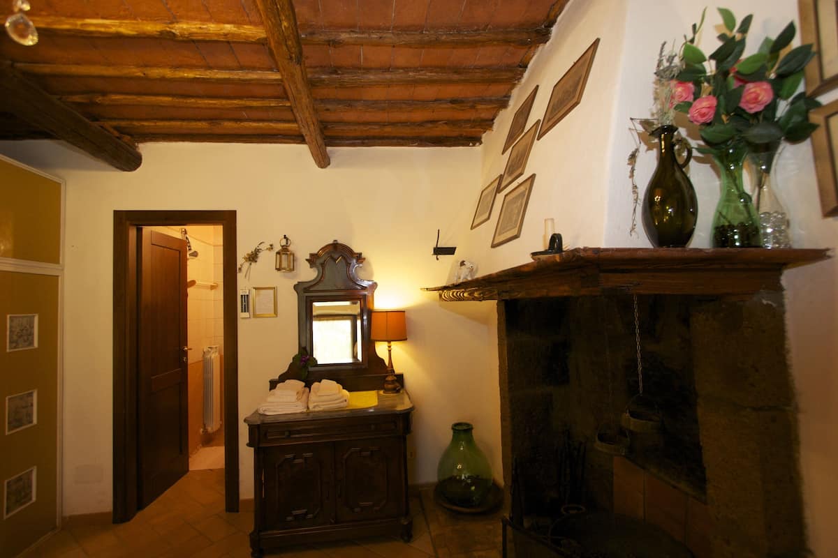 A traditional room with a wooden ceiling, a fireplace, a mirror, and a dresser.