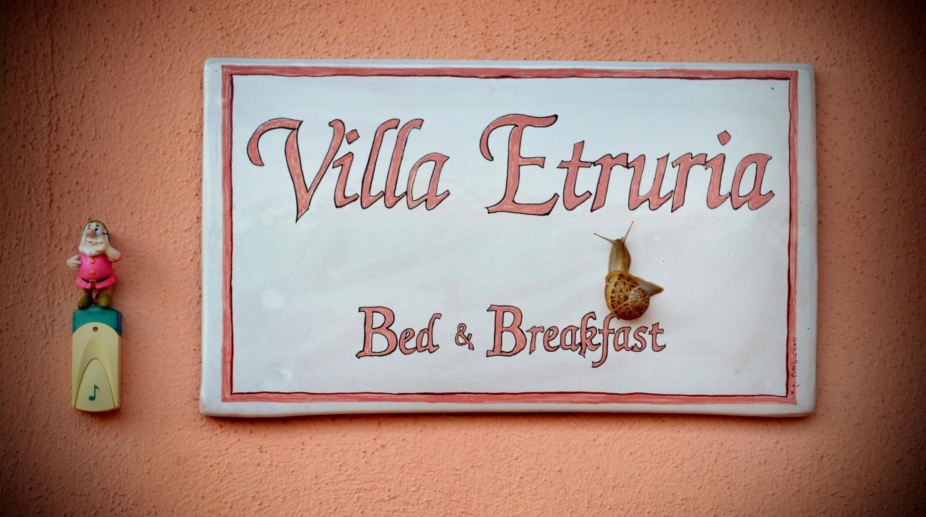 A sign for Villa Etruria Bed & Breakfast with a snail decoration.