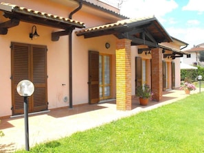 A two-story house with a tiled roof, wooden shutters, and a brick column. - Villa Etruria Guest House (Pitigliano)