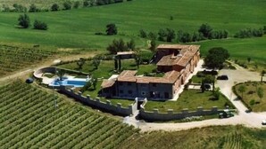A large estate with a main building surrounded by lush green fields and a vineyard. - Agriturismo Le Ginestre (Manciano)