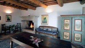 A rustic room with a fireplace, wooden furniture, and a cabinet with decorative plates. - Agriturismo Le Ginestre (Manciano)