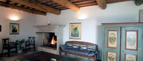 Una habitación rústica con chimenea, muebles de madera y un aparador con placas decorativas.