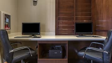 A workspace with two monitors, a printer, and two office chairs.