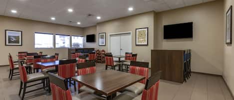 A conference room with multiple tables and chairs, a television, and framed artwork on the walls.