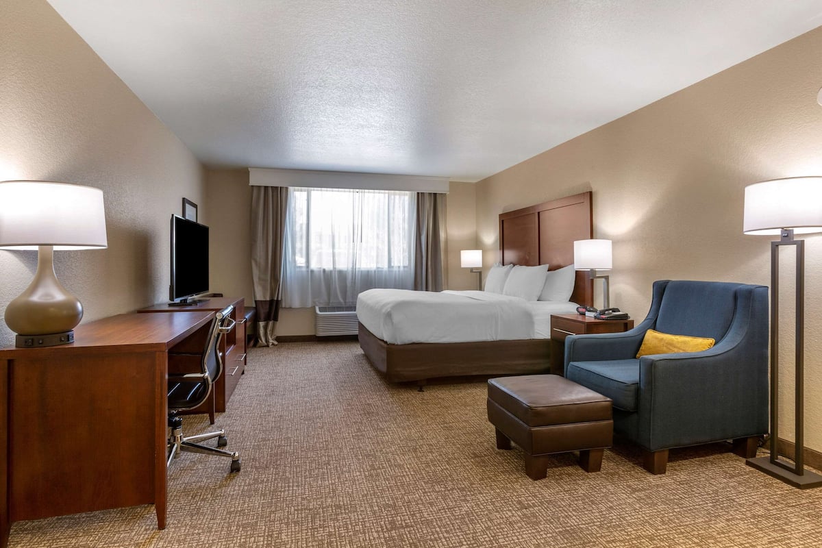 Ein Hotelzimmer mit Bett, Schreibtisch, Stuhl und Fernseher.