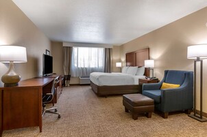 A hotel room with a bed, desk, chair, and a television.