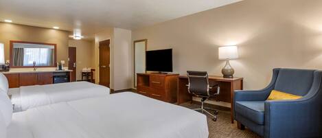 A hotel room with two beds, a desk with a chair, a television, and a lamp.