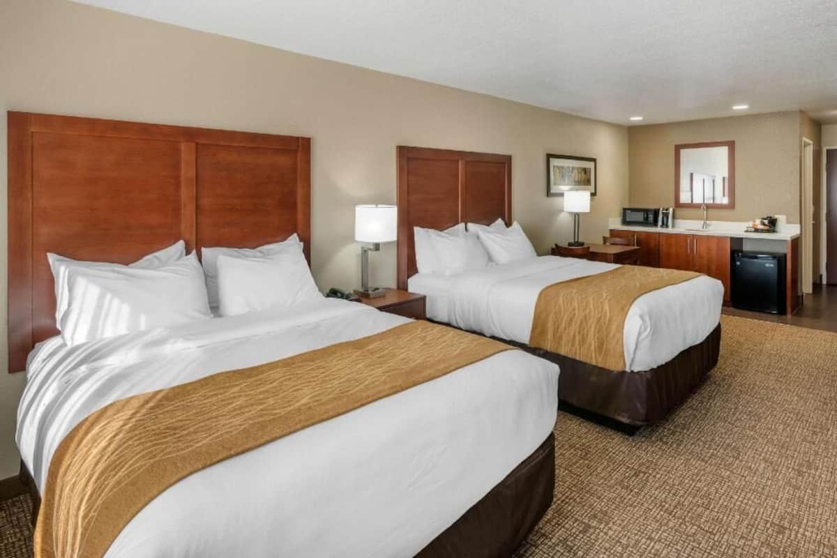 Ein Hotelzimmer mit zwei Betten, einer Küchenzeile und einem Badezimmer.