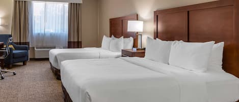 A hotel room with two beds, a desk, a chair, and a window with curtains.