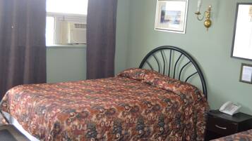 A bedroom with a bed, a bedside table, a lamp, and a window with curtains.