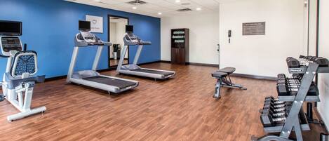 A gym with treadmills, a stationary bike, and a weight bench.