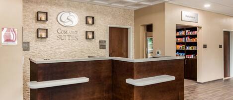 A hotel reception area with a brick wall, a sign for 'Comfort Suites', and a 'Marketplace' sign.