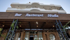 A Bar Restaurant with a wooden facade and a covered entrance. - Hotel Horizont (Aliko)