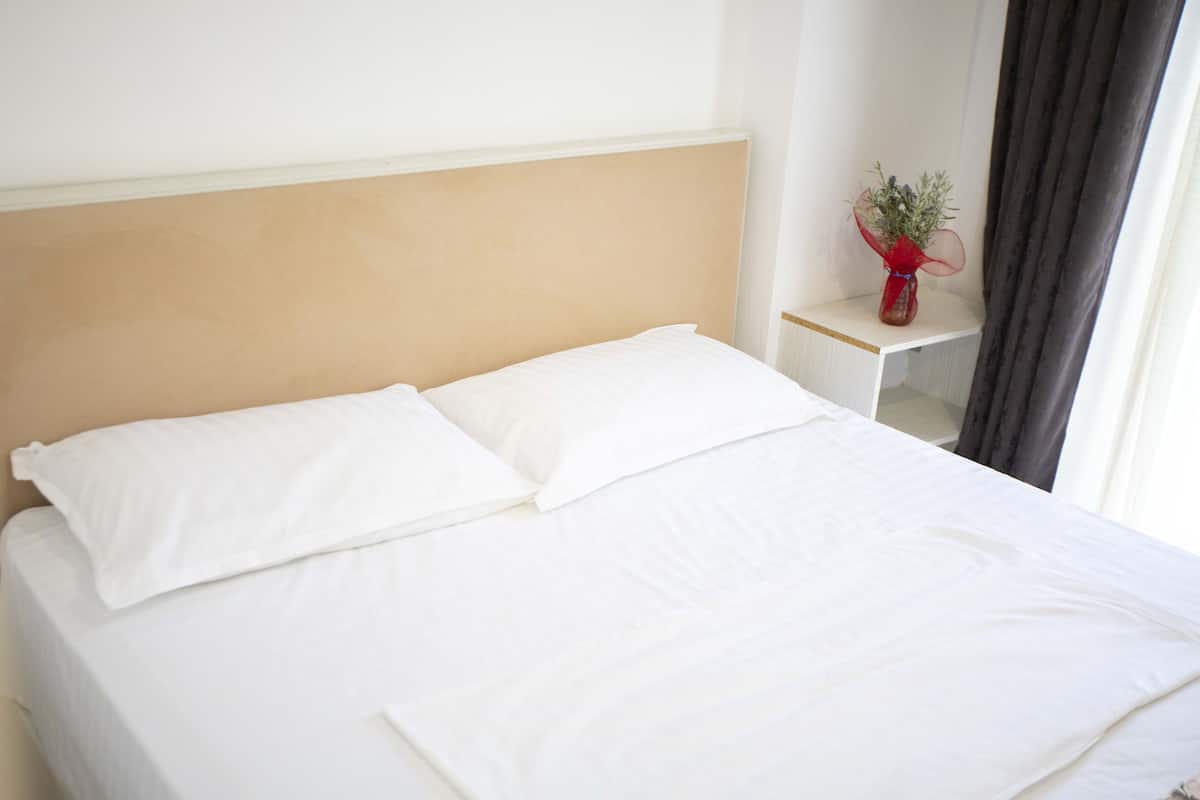 A neatly made bed with white linens in a hotel room.