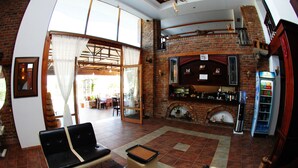 A spacious living area with a fireplace, seating, and a bar area. - Hotel Horizont (Aliko)
