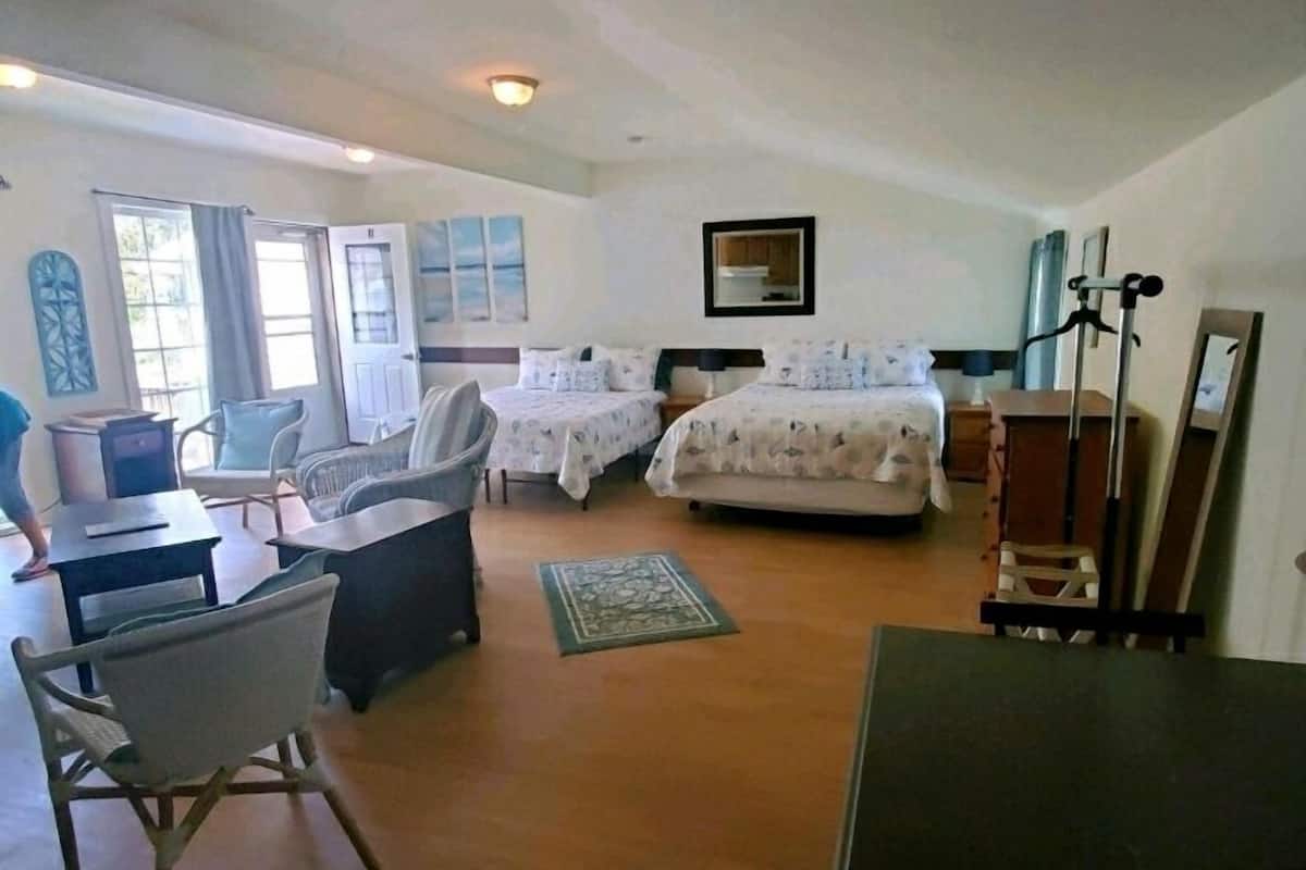 A spacious bedroom with two beds, a desk, a chair, and a large mirror.
