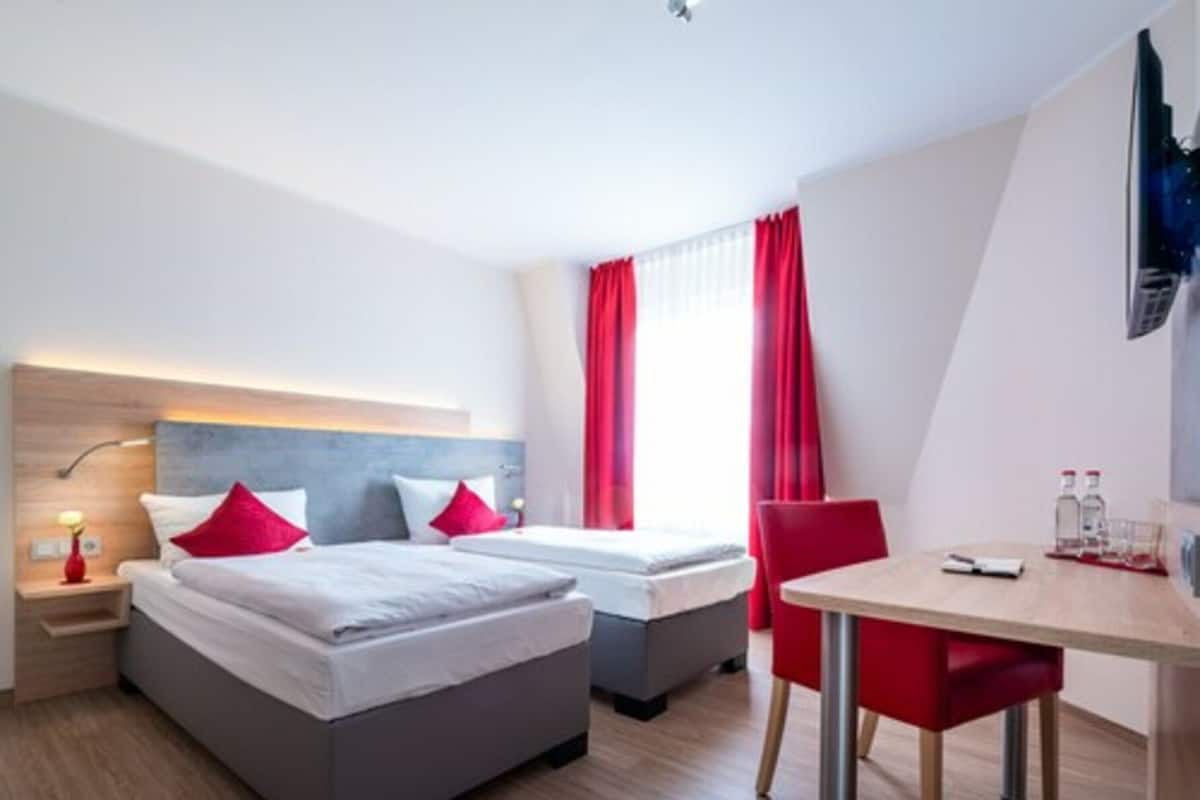 A hotel room with two beds, a desk, and a chair.