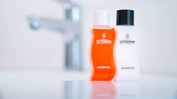 Two bottles of Fettehenné shower gel and shampoo on a reflective surface.