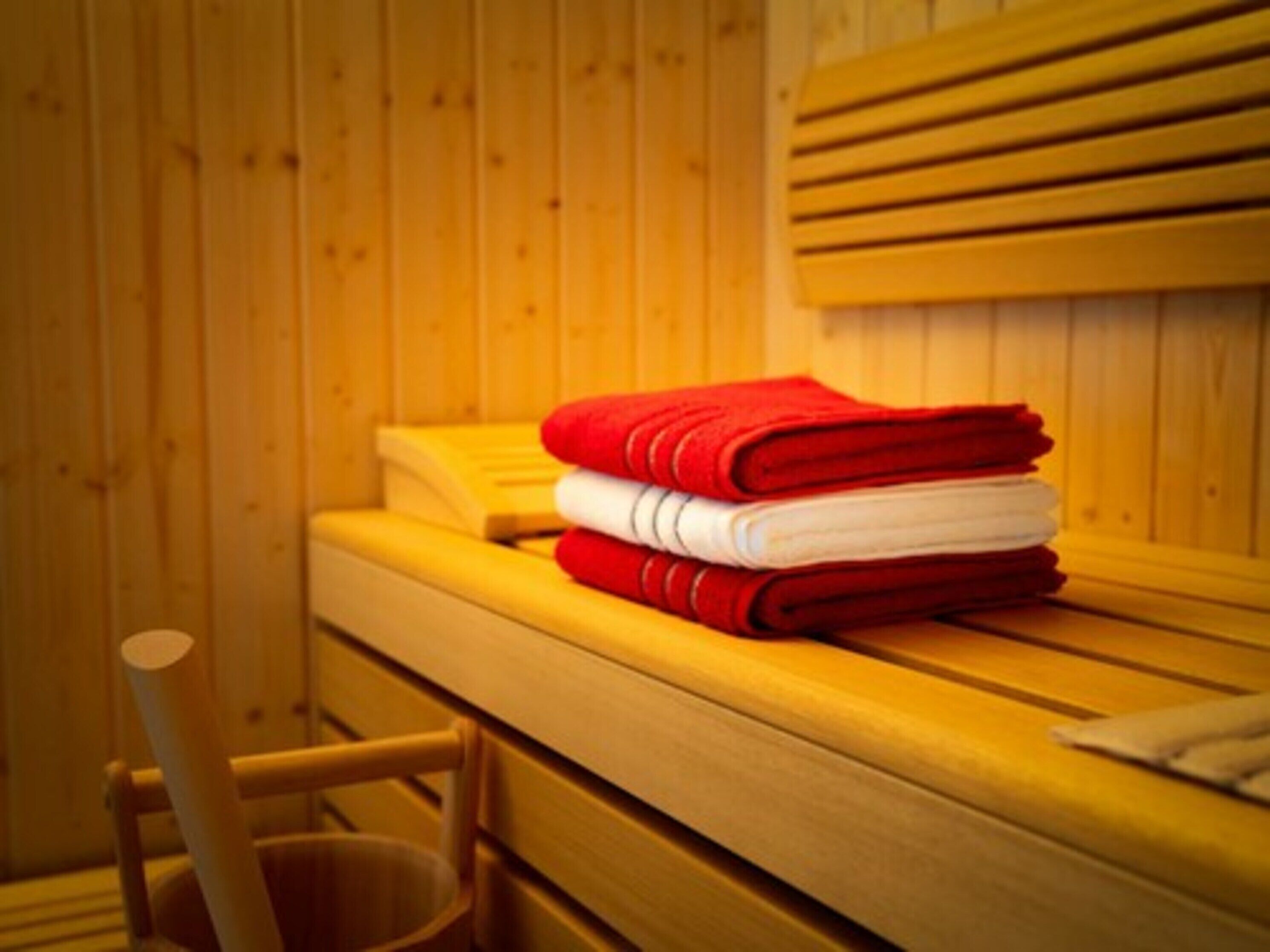 A wooden cabin with a bed, a chair, and a stack of folded towels.