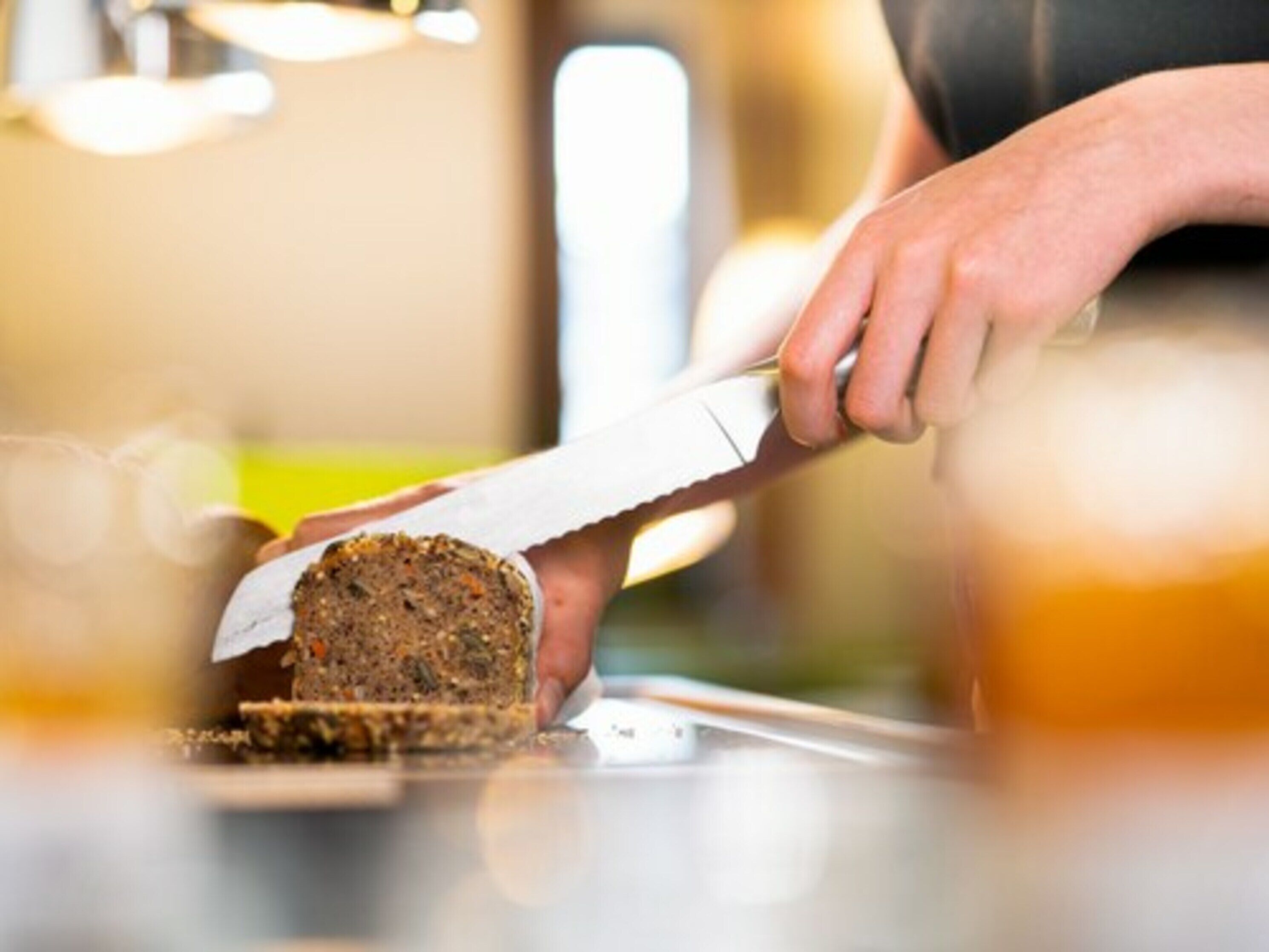 A person slicing a loaf of bread on a counter.