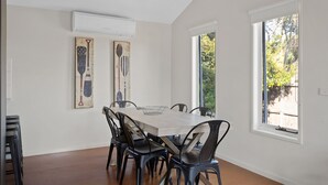 A dining area with a large table, black chairs, and two artworks on the walls. - Cowes Retreat - *Pet Friendly* Holiday House!!! (Cowes)