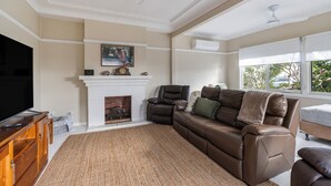 A living room with a fireplace, leather sofa, and a television.