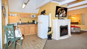 A kitchen with wooden cabinets, a white refrigerator, a microwave, and a bear statue holding a sign. - Gatlinburg Cabin Free Tickets, Heart Whirlpool, Hot Tub, King Bed, Fast Internet (Gatlinburg)