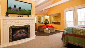 A bedroom with a fireplace, a television mounted above it, and a large mirror on the wall. - Gatlinburg Cabin Free Tickets, Heart Whirlpool, Hot Tub, King Bed, Fast Internet (Gatlinburg)
