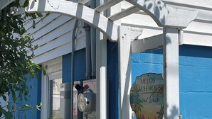 A blue building with a white gate and a sign that reads "Melos Ach House." - Lower deck, Salisbury Beach, Melo's Beach House Rentals  (Salisbury)
