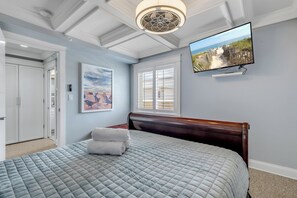 Un dormitorio con cama, un cuadro, televisor y vista a la playa.