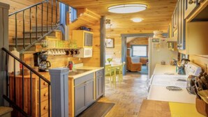 A wooden interior with a kitchen, dining area, and staircase.