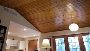 A kitchen with wooden ceiling, white cabinets, a window with blinds, and a hanging light fixture. - Harbor Haven: A Summer Getaway Just Steps from Lake Michigan (Union Pier)