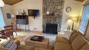A living room with a stone fireplace, a television, and a sofa. - Harbor Haven: A Summer Getaway Just Steps from Lake Michigan (Union Pier)
