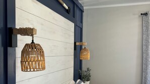 A bedroom with a striped bedspread, multiple pillows, a wooden headboard, and two hanging light fixtures. - Ocean wave, Salisbury Beach, Melo's Beach House rentals (Salisbury)