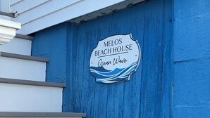 A sign for Melos Beach House with a wave design, located next to a set of stairs. - Ocean wave, Salisbury Beach, Melo's Beach House rentals (Salisbury)