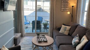 A cozy living room with a sofa, a coffee table, and a TV mounted on the wall. - Ocean wave, Salisbury Beach, Melo's Beach House rentals (Salisbury)