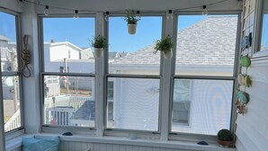 A sunroom with a white bench, a small table, and potted plants. - Ocean wave, Salisbury Beach, Melo's Beach House rentals (Salisbury)