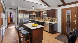 Una cocina moderna con armarios de madera oscura, electrodomésticos de acero inoxidable y una isla central con un cuenco de frutas.