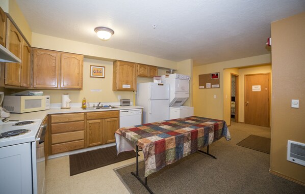 A compact kitchen with wooden cabinets, a microwave, a refrigerator, and a stove.