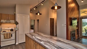 A modern kitchen with a marble countertop, wooden cabinets, a built-in oven, and pendant lighting. - DOCKSIDE DAYS-LAKEFRONT in Lake Naomi!  Boating, Sunsets and Year-Round Fun (Pocono Pines)