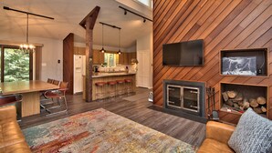 A spacious living area with a wooden wall, a fireplace, and a large TV mounted on the wall. - DOCKSIDE DAYS-LAKEFRONT in Lake Naomi!  Boating, Sunsets and Year-Round Fun (Pocono Pines)