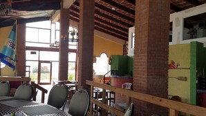 Een restaurant met een rustiek interieur, met zichtbare bakstenen muren, houten balken en zowel binnen- als buitenterras.