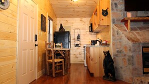 Un interior de madera con chimenea de piedra, armarios de madera y una estatua de un oso.