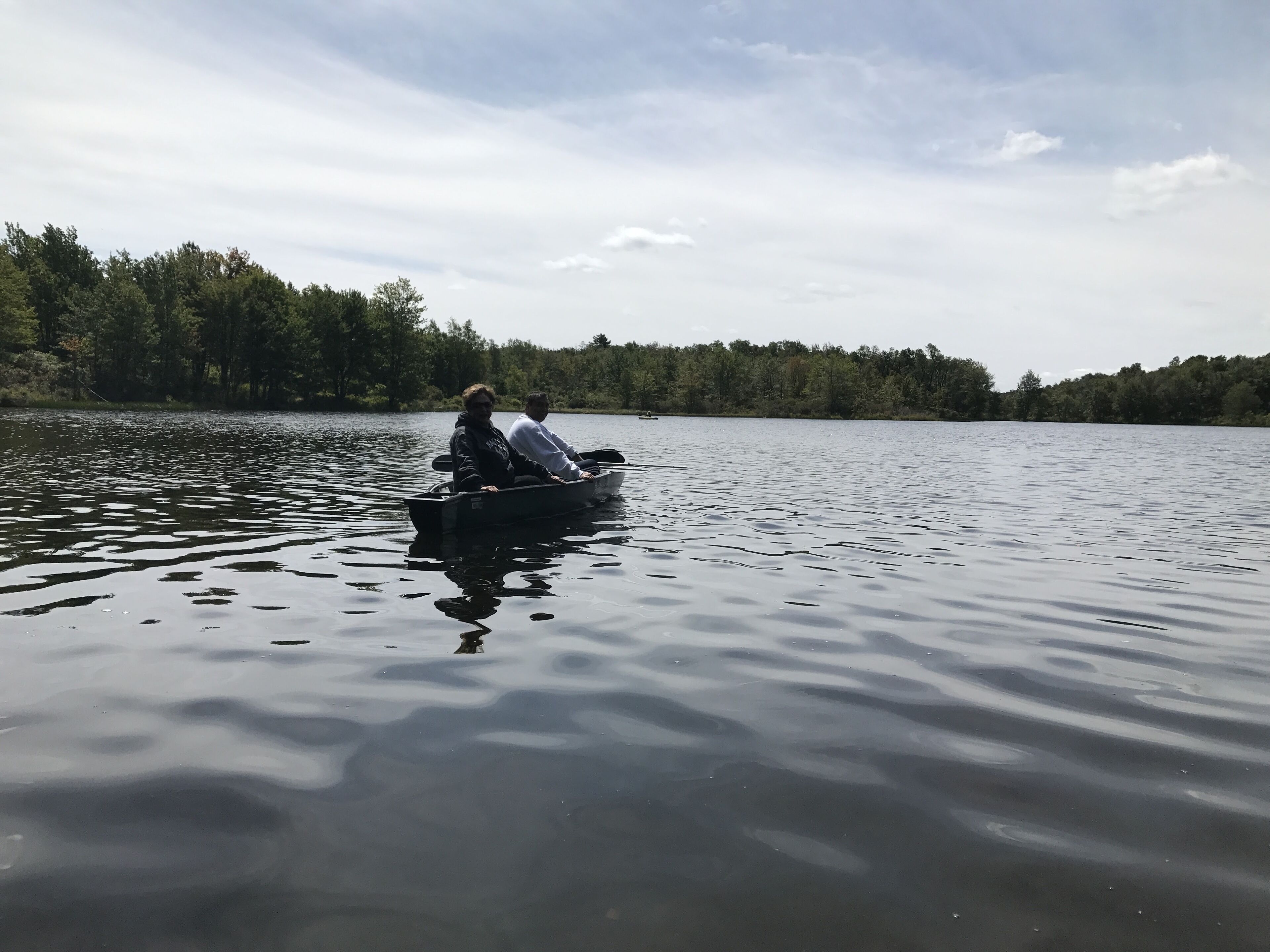 A calm lake with a boat carrying two people.