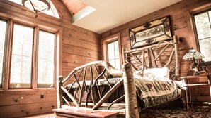 A rustic wooden room with a unique bed frame, large windows, and a traditional lamp.