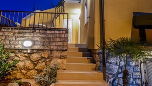 Una escalera conduce a un edificio con un muro de piedra y barandilla de metal.