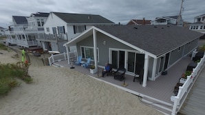 Ett hus vid stranden med en terrass, utomhusmöbler och utsikt över stranden.