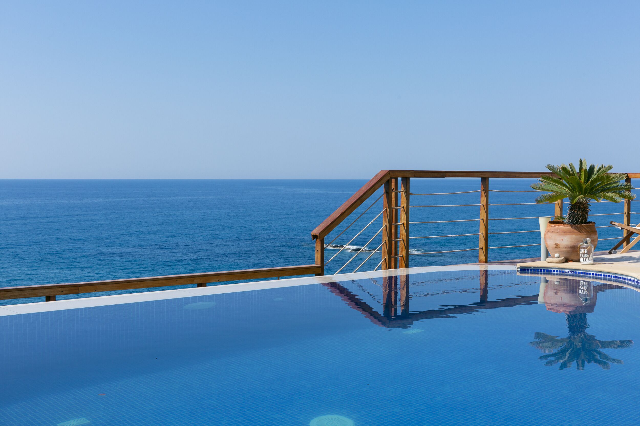 Una piscina con muelle de madera y vista al océano.