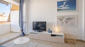 Un salon moderne avec un téléviseur à écran plat, une carte du monde et un tableau représentant une plage.
